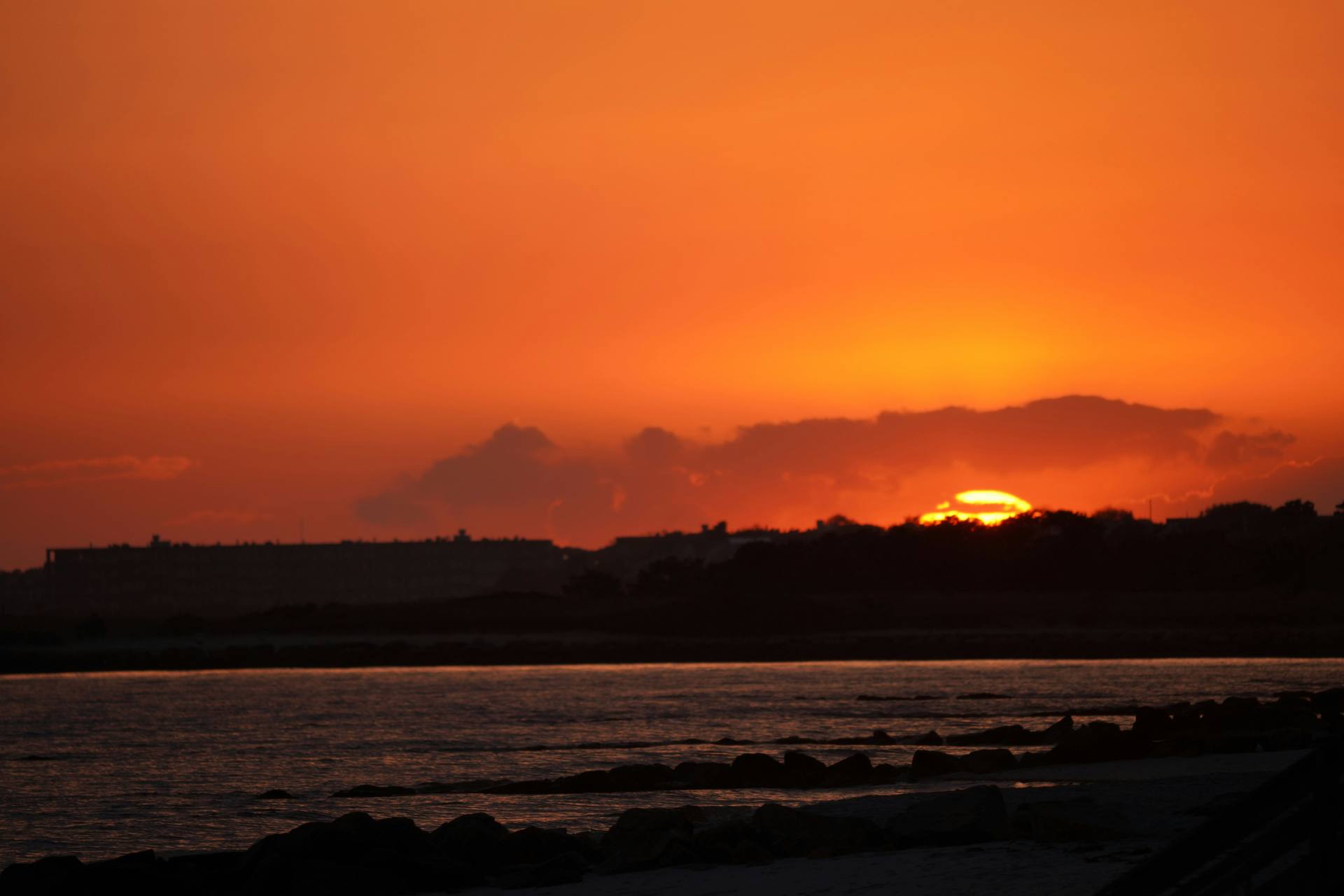 Orange sunset over a rocky shoreline, photographed by Howard Wang